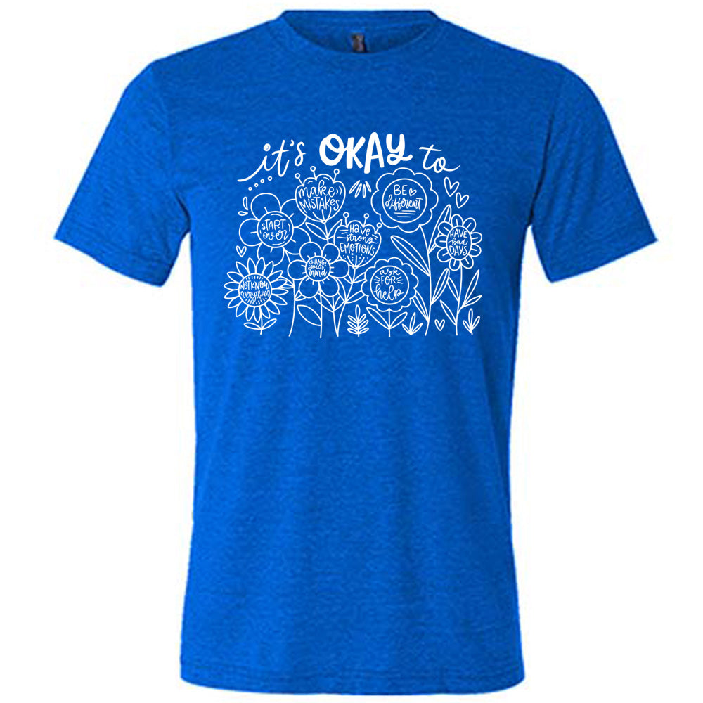 blue unisex tee with the words "it's okay to" on it, and underneath there are many flowers that each have the completion of that phrase; the different endings are "make mistakes", "be different", "have bad days", "ask for help", "have strong emotions", "change your mind", "Start over", and "not know everything".