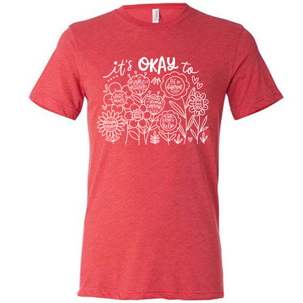 red unisex tee with the words "it's okay to" on it, and underneath there are many flowers that each have the completion of that phrase; the different endings are "make mistakes", "be different", "have bad days", "ask for help", "have strong emotions", "change your mind", "Start over", and "not know everything".
