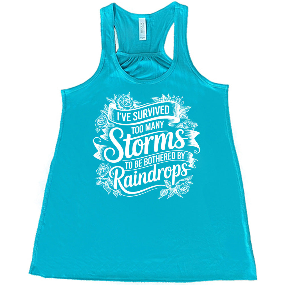 Teal Flowy Tank, with wording I've Survived Too Many Storms to be Bothered by Raindrops, banners and flowers