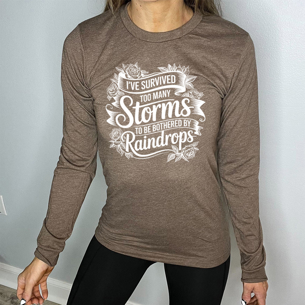Heather Brown Long Sleeve, with wording I've Survived Too Many Storms to be Bothered by Raindrops, with banners and flowers