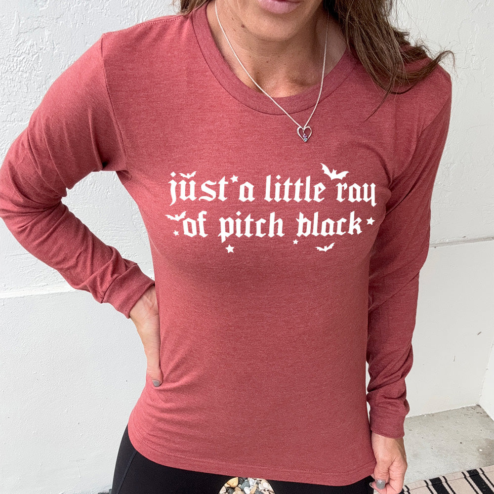 heather clay long sleeve shirt with the words "just a little ray of pitch black" on it in a medieval font, with little bats and stars accenting the words