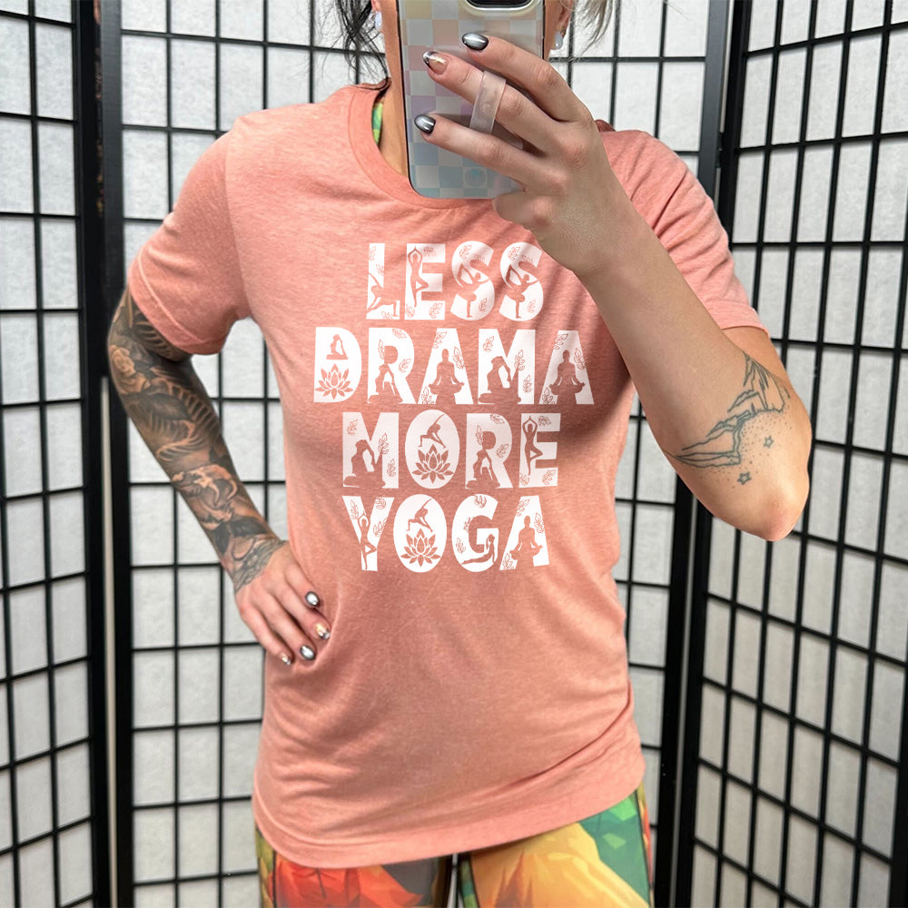 sunset unisex tee with the words "less drama more yoga" on it, and within each letter there are silhouettes of people doing yoga poses as well as some lotus flowers and some leaves