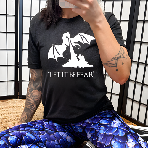 model wearing a black unisex shirt with a white dragon graphic and the saying "Let It Be Fear" on it in white