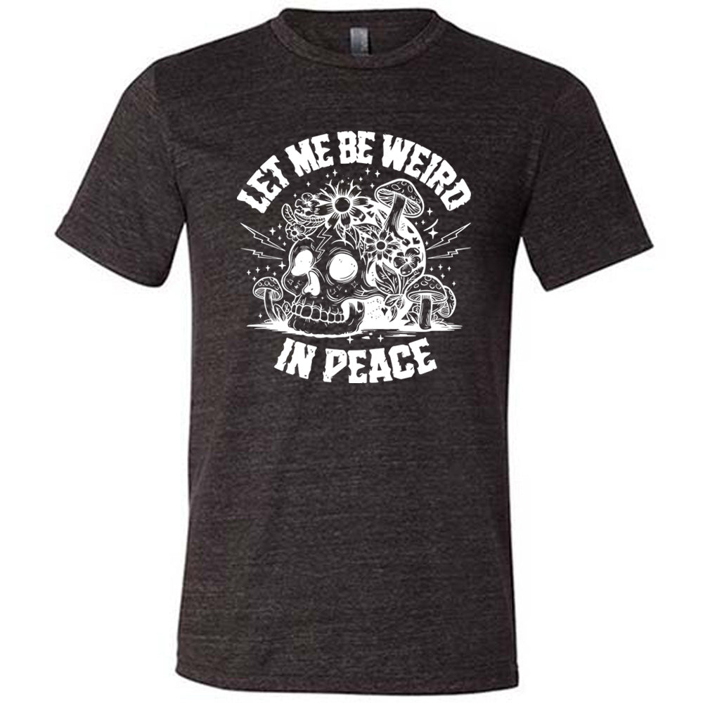 black unisex tee with the words "let me be weird in peace" on it with the graphic of a skull on the ground with mushrooms growing on and around it, as well as flowers growing on it, surrounded by little stars and lightening bolts