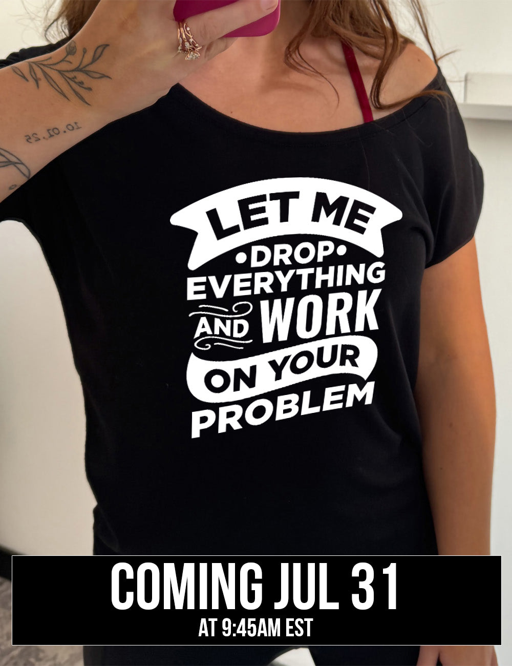 black slouchy tee with the words, some of them bannered or embellished, saying "Let me drop everything and work on your problem" , coming july 31st