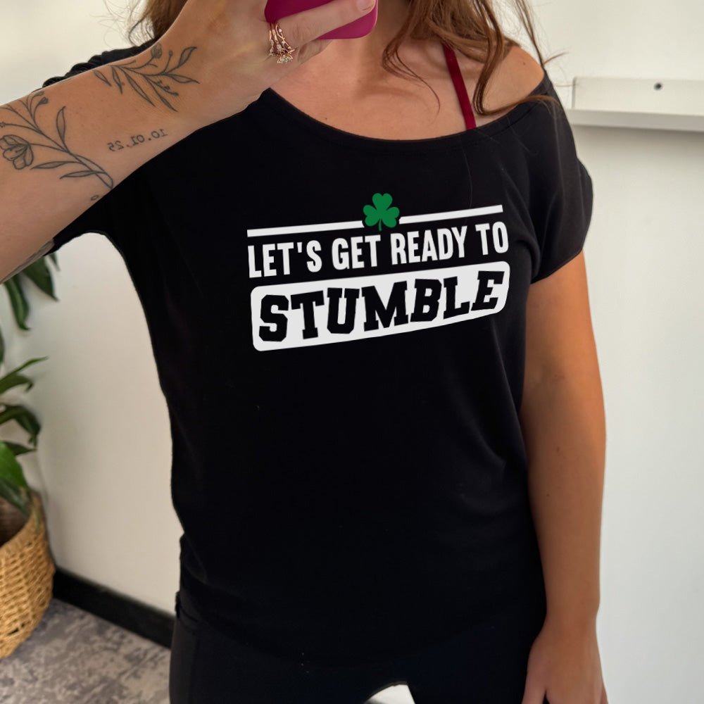 black slouchy tee with the words "let's get ready to stumble" on it, with one little shamrock graphic, and the word "stumble" in a rectangular block, and the letters leaning in different directions
