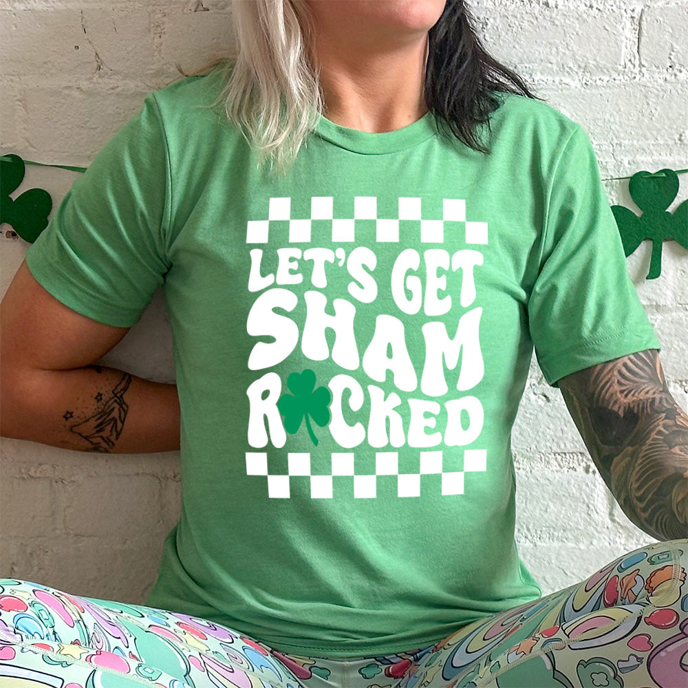 lucky green tee with the words "let's get shamrocked" on it, with a shamrock graphic replacing the "o" of "rocked", and a checkerboard border on top and bottom of the words