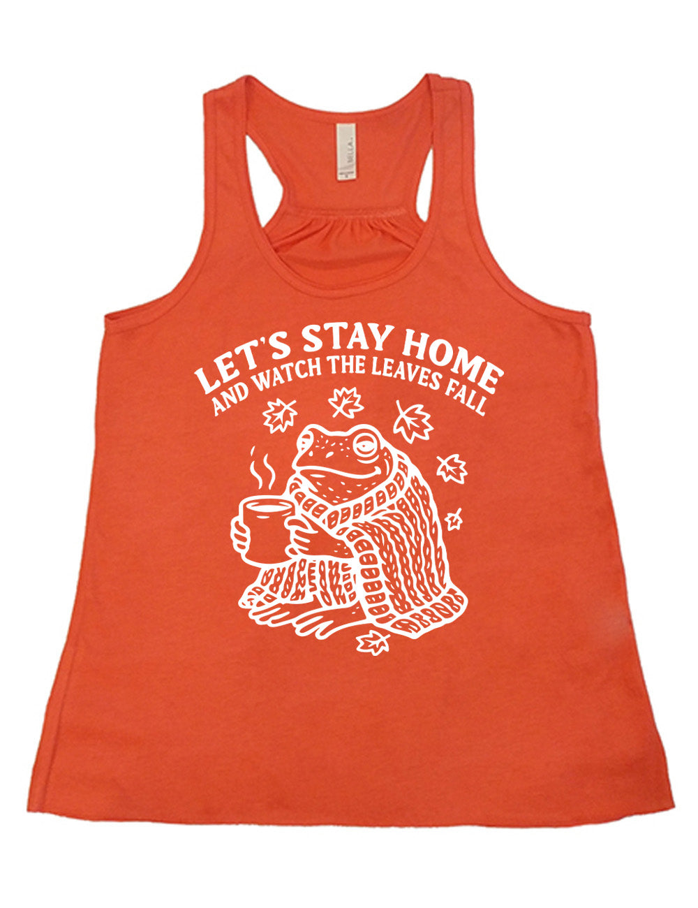 coral flowy racerback tank with the words "let's stay home and watch the  leaves fall" on it, and the graphic underneath of a frog, wrapped in a blanket, holding a mug of steaming beverage, with five leaves arching over it