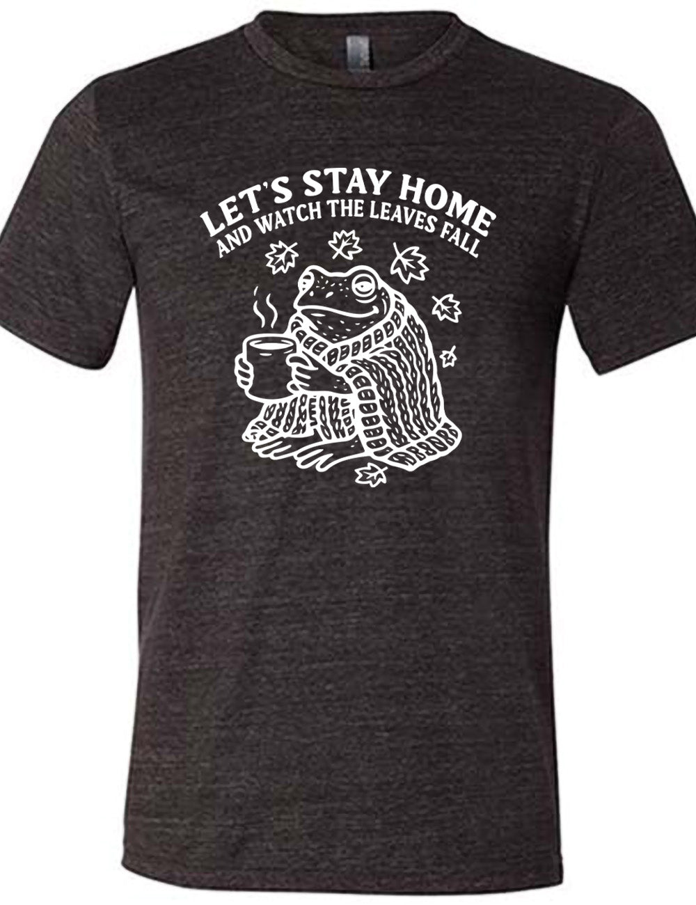 black unisex tee with the words "let's stay home and watch the  leaves fall" on it, and the graphic underneath of a frog, wrapped in a blanket, holding a mug of steaming beverage, with five leaves arching over it