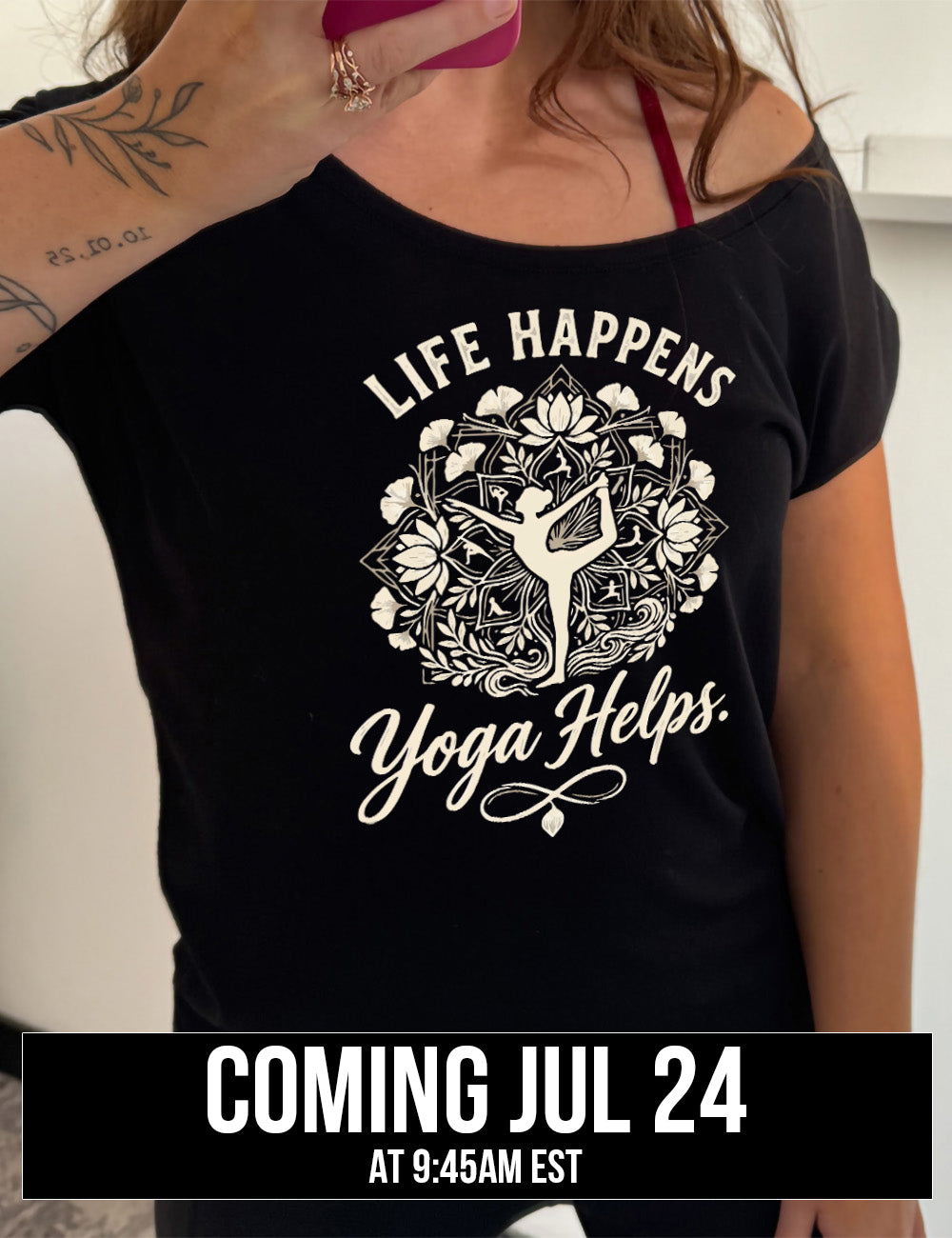 black slouchy tee with the words "life happens yoga helps." on it, around the graphic of a woman's silhouette doing a yoga pose in the middle of a elaborate pattern of shapes, lotuses and other plants, coming july 24th