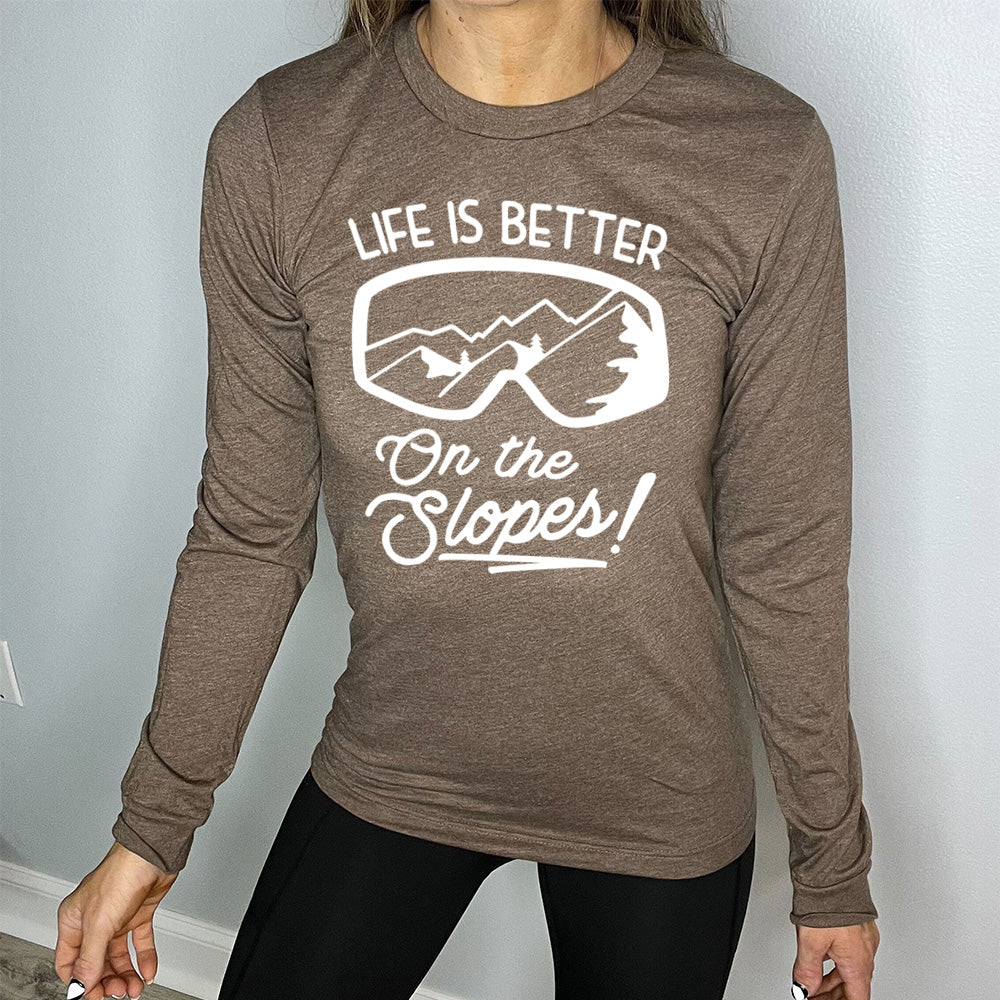 Heather brown long sleeve with the words "Life is better on the slopes!" with the image of snow goggles and a reflection of the slopes in them