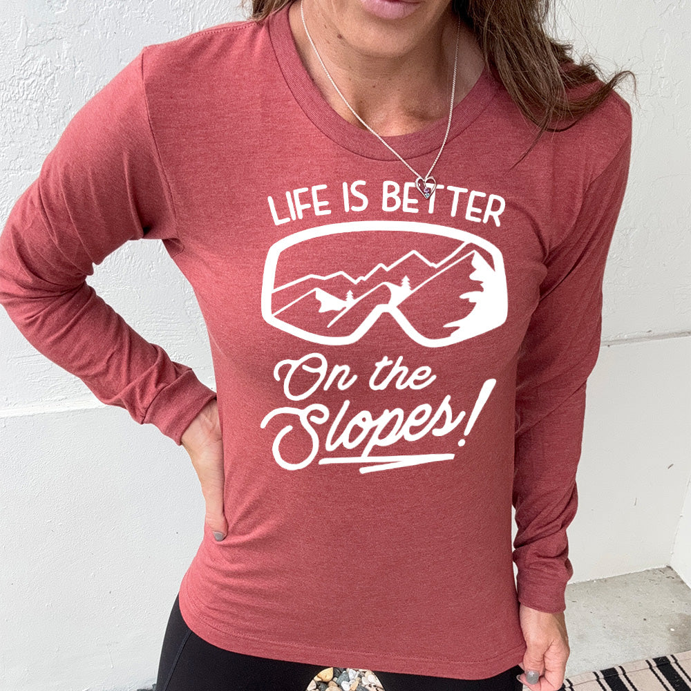 Heather clay long sleeve with the words "Life is better on the slopes!" with the image of snow goggles and a reflection of the slopes in them