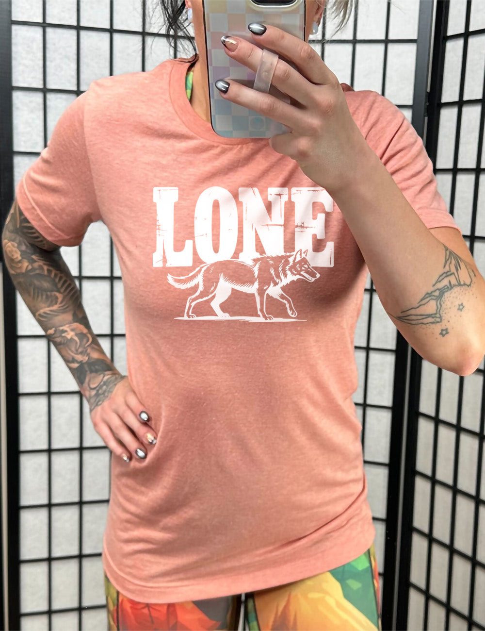 sunset unisex tee with the large all caps word "lone" on it, with a wolf graphic underneath