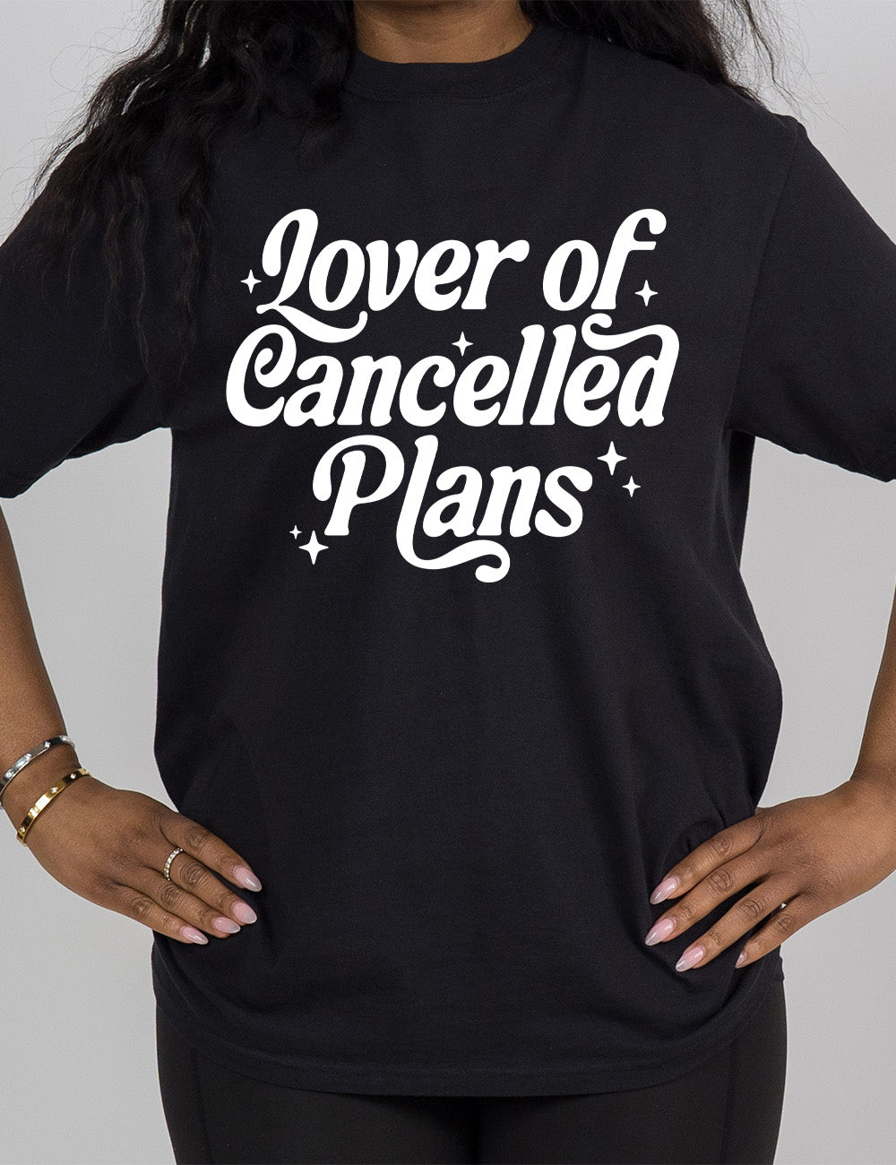 black modern tee with the words on it saying "lover of cancelled plans" with a few stars around the words