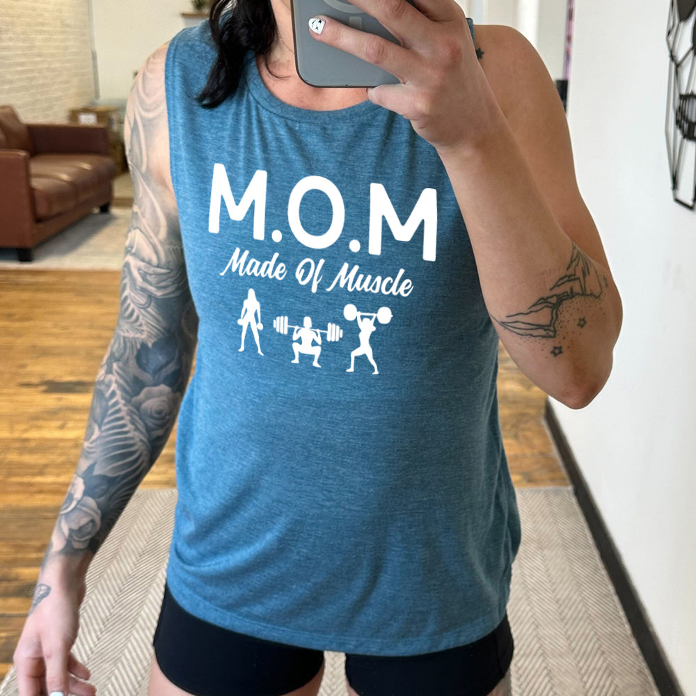 deep teal muscle tank with the word "mom" in large letters as an acronym for the smaller words below it saying "made of muscle", and the graphic of three female silhouettes holding weights