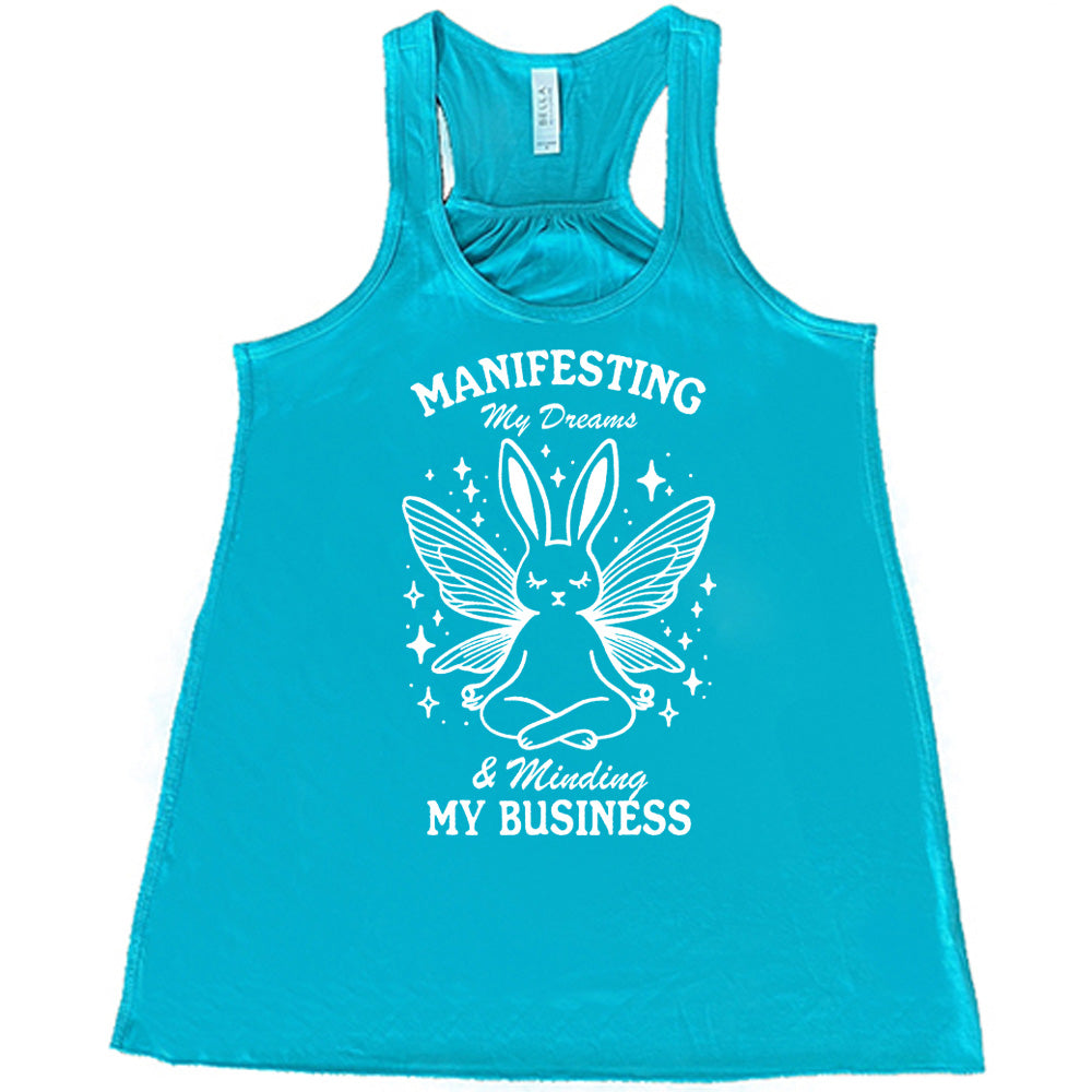 Teal flowy tank with the words "Manifesting My Dreams & Minding My Business" and the graphic of a meditating rabbit with butterfly wings