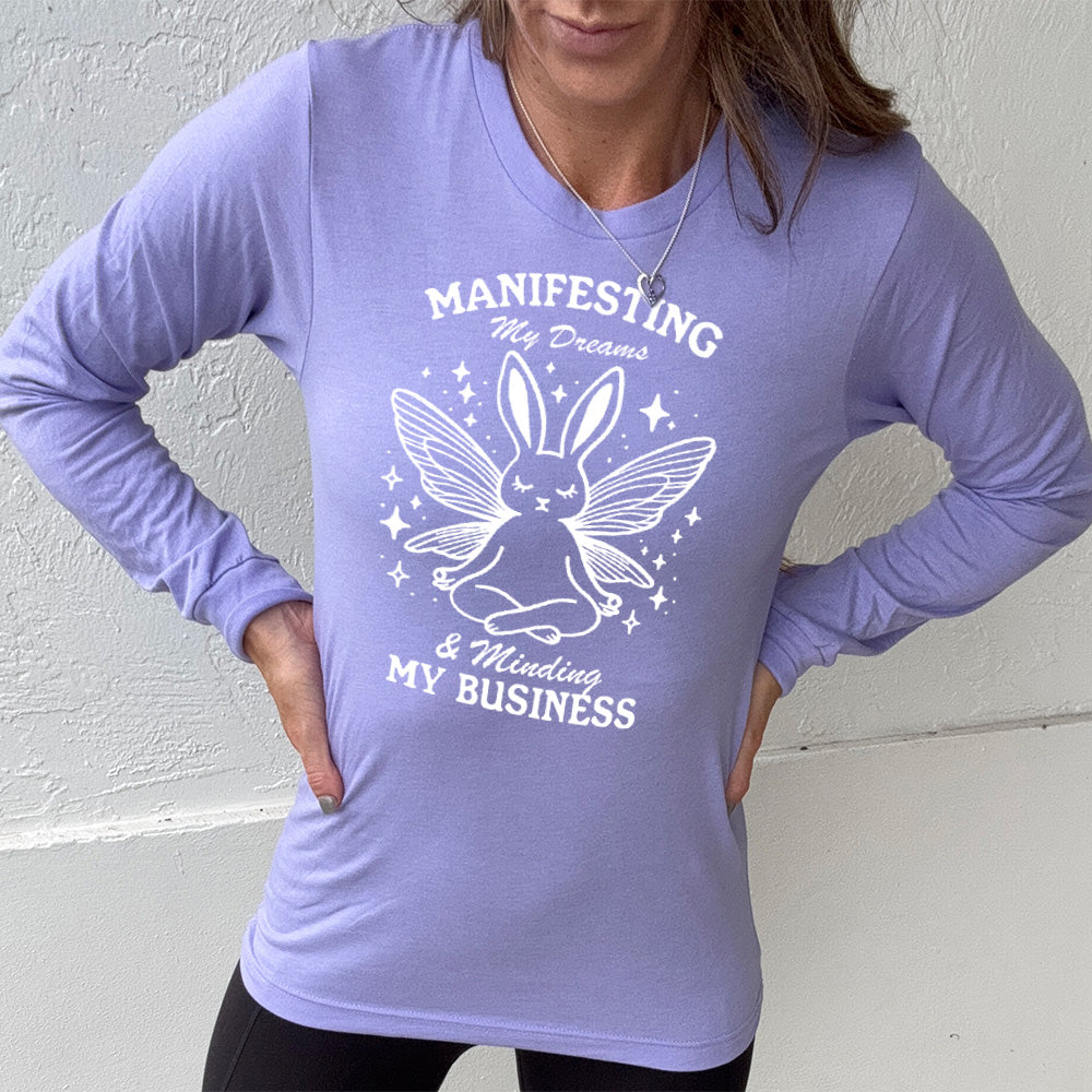 Heather Dark Lavender long sleeve shirt with the words "Manifesting My Dreams & Minding My Business" and the graphic of a meditating rabbit with butterfly wings
