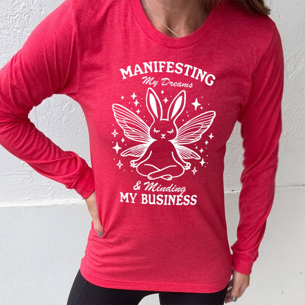 Heather Red long sleeve shirt with the words "Manifesting My Dreams & Minding My Business" and the graphic of a meditating rabbit with butterfly wings