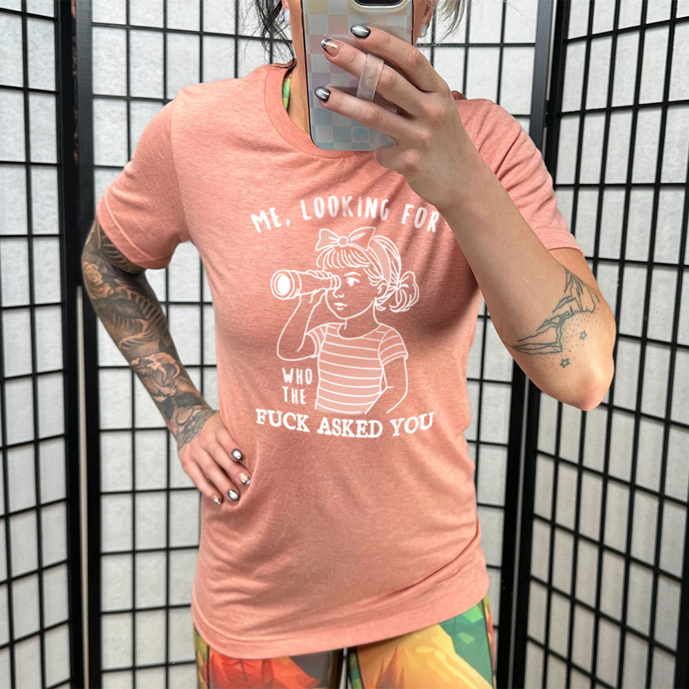 sunset unisex tee with the graphic of a young girl, wearing a striped pink shirt and a pink bowed headband and looking through a telescope, and the words "me, looking for who the fuck asked you" on it
