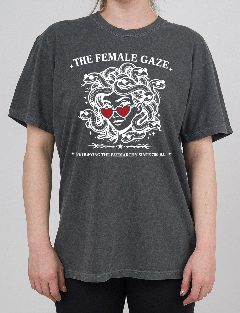 pepper modern tee with the detailed graphic of medusa, wearing red heart sunglasses, with sunglass-wearing snakes for hair, and the words above saying "THE FEMALE GAZE" with a little star on either end, and the smaller words below saying "petrifying the patriarchy since 700 B.C."