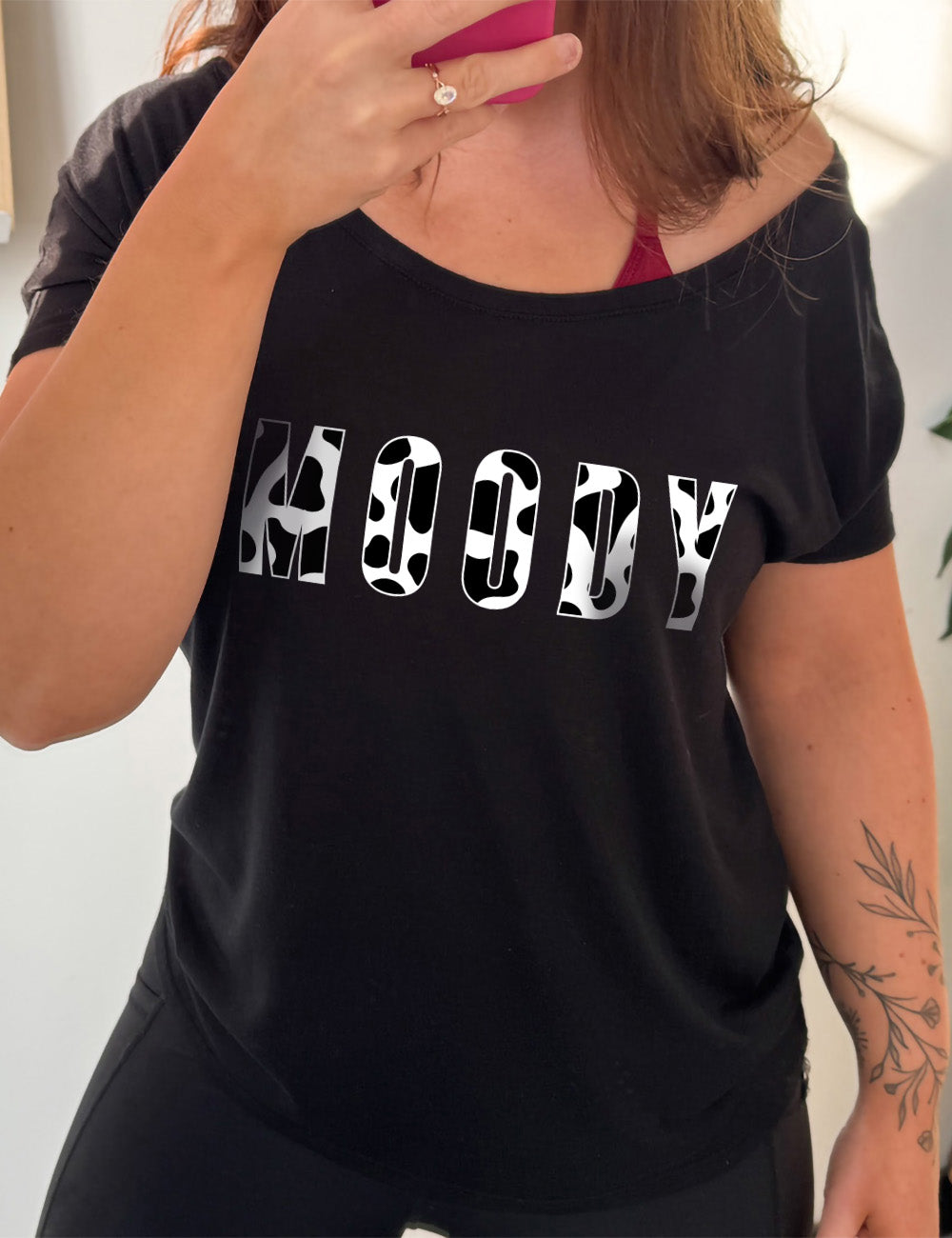black slouchy tee with the word "moody" in all caps on it, with the font being cow print