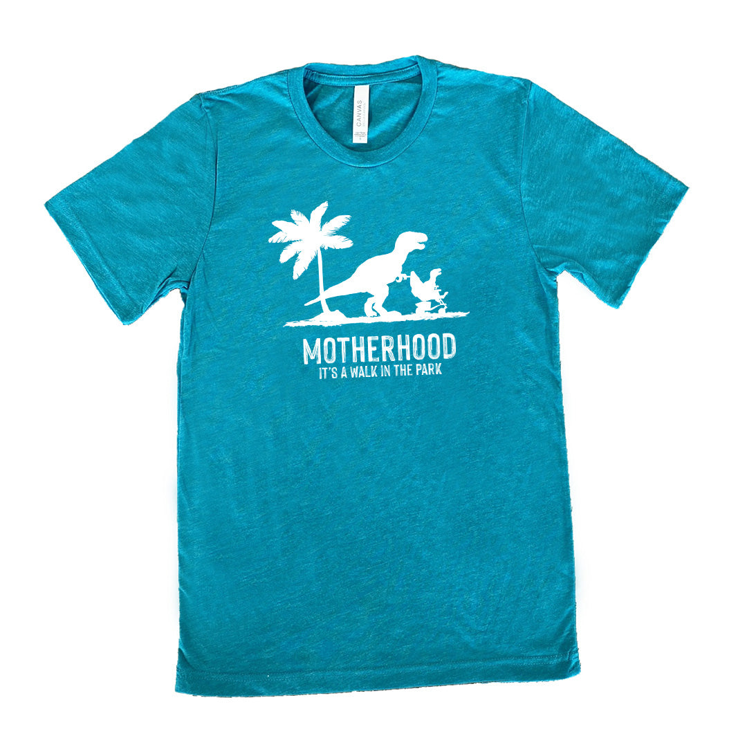 Teal colored shirt with a mother and child dinosaur graphic on it that says "Motherhood, Its a Walk in the Park" 