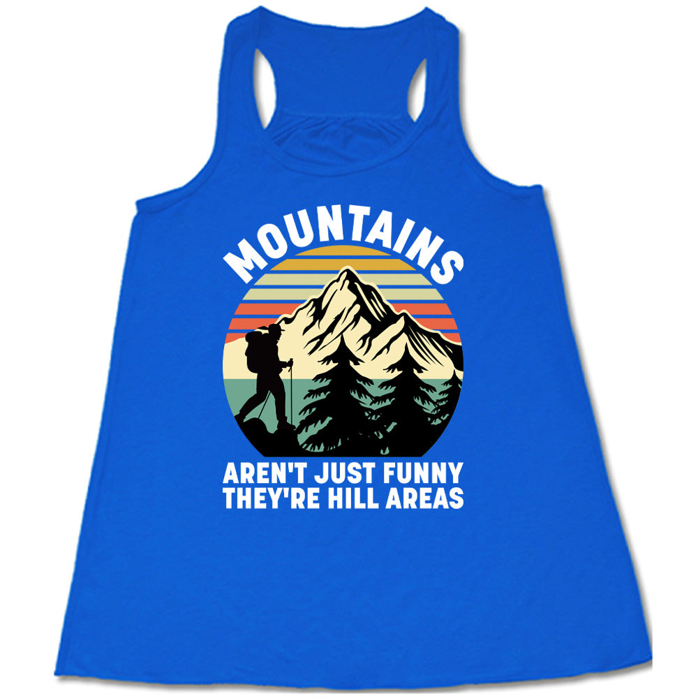 blue flowy tank with the words "mountains aren't just funny they're hill areas" on it, with the graphic of a mountain, trees, a colorful sky, and the silhouette of a hiker