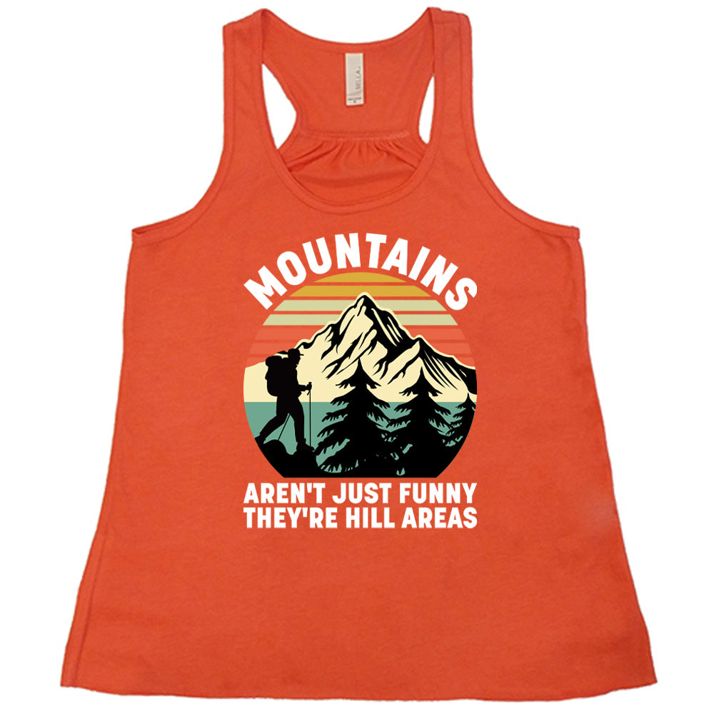coral flowy tank with the words "mountains aren't just funny they're hill areas" on it, with the graphic of a mountain, trees, a colorful sky, and the silhouette of a hiker