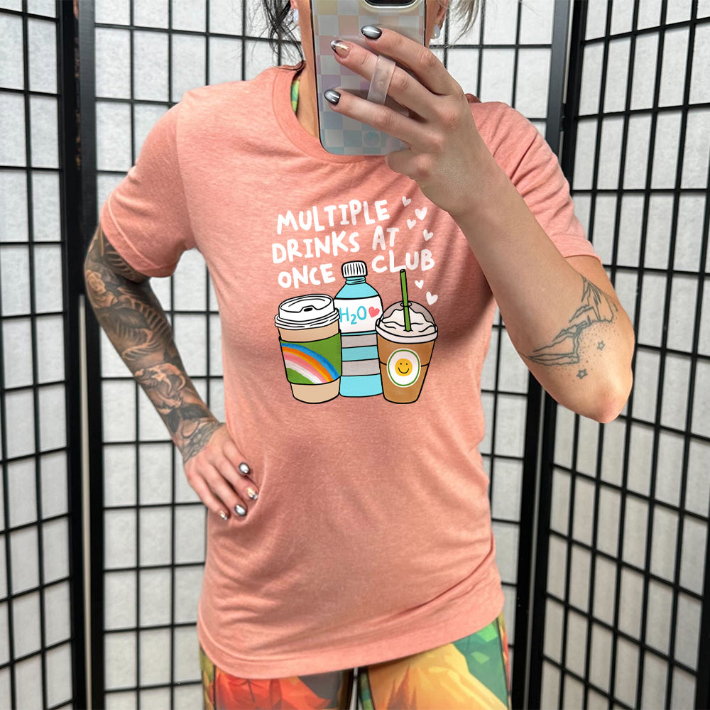 Model wearing sunset colored shirt with an assorted cup collection graphic on it that says "Multiple Drinks at Once Club" 