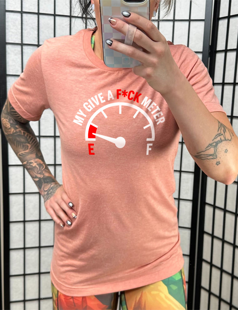 sunset unisex tee with the graphic of a fuel gauge, with the marker on empty, and the words arching over the meter saying "my give a f*ck meter"