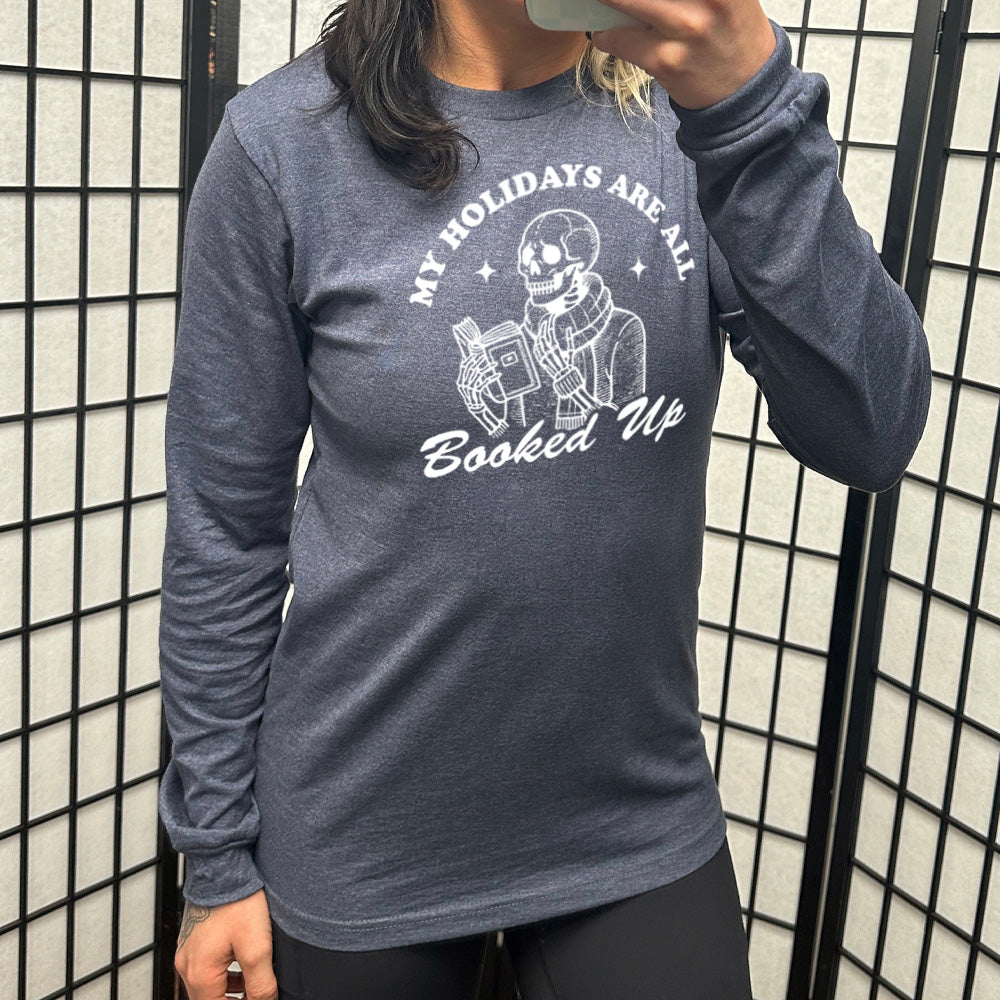heather navy long sleeve with the words "my holidays are all booked up", with the image of a skeleton dressed warmly and reading a book