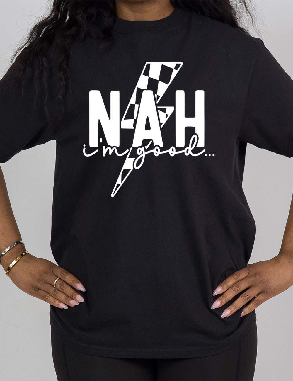black modern tee with the large word "NAH" and small lowercase cursive words underneath saying "i'm good", and the graphic of a checkered lightning bolt behind the words