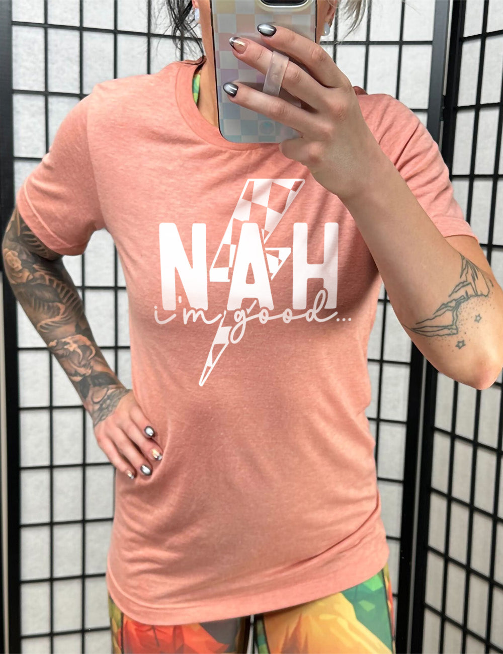 sunset unisex tee with the large word "NAH" and small lowercase cursive words underneath saying "i'm good", and the graphic of a checkered lightning bolt behind the words