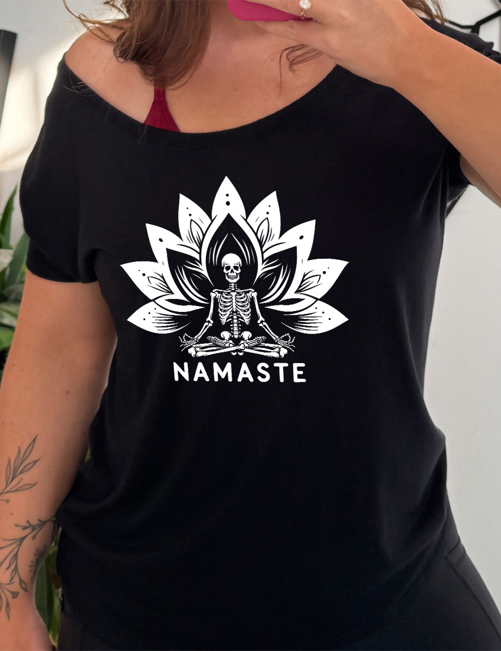 black slouchy tee with the graphic of a skeleton doing a seated yoga pose among a double lotus graphic, with the words underneath saying "namaste"