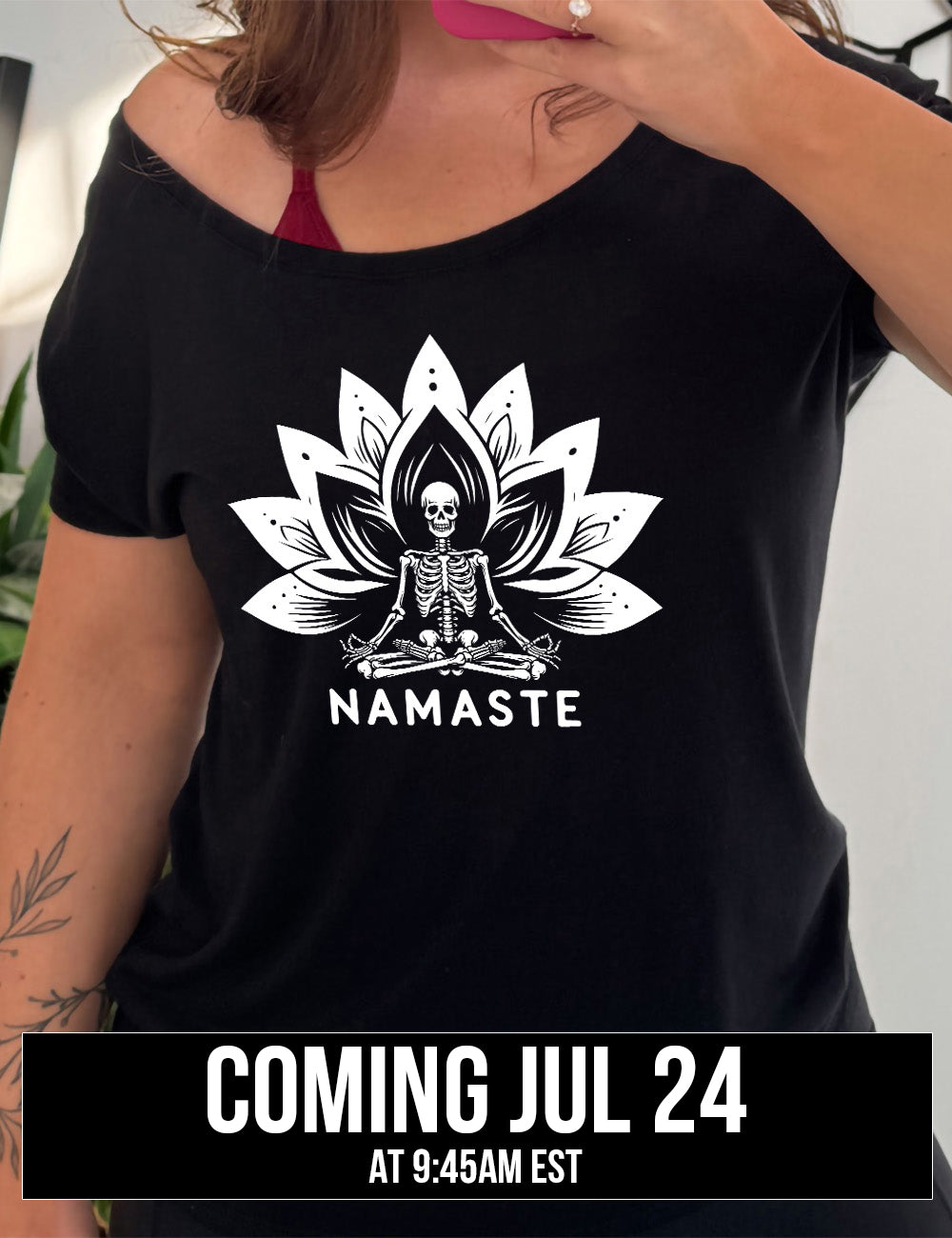 black slouchy tee with the graphic of a skeleton doing a seated yoga pose among a double lotus graphic, with the words underneath saying "namaste" coming july 24th