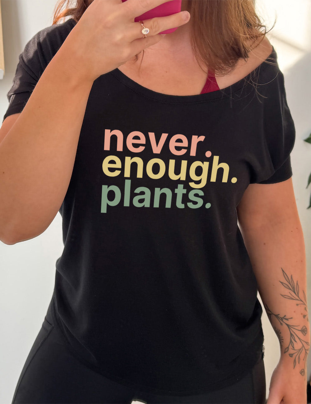 black slouchy tee with three words stacked on top of each other, with periods, that say "never. enough. plants." 