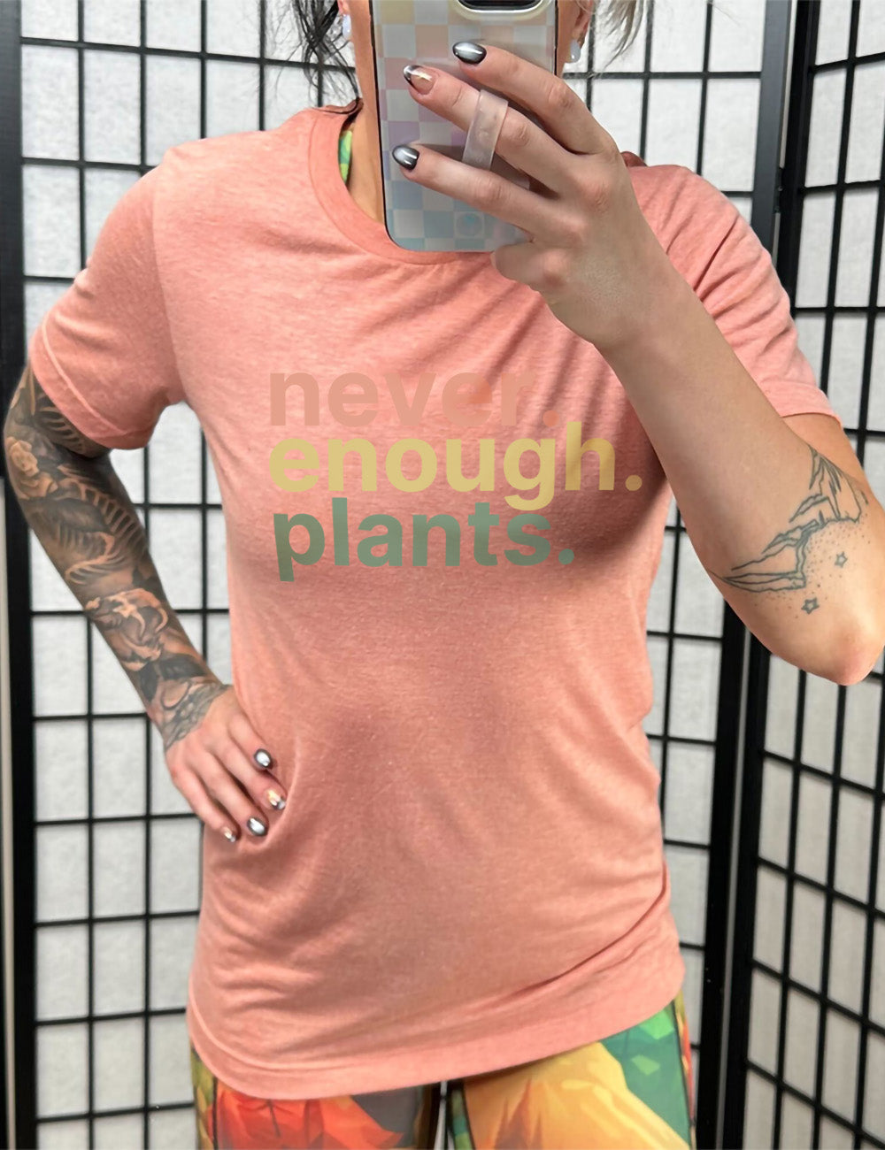 sunset unisex tee with three words stacked on top of each other, with periods, that say "never. enough. plants." 