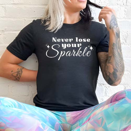 model wearing a black unisex shirt with the saying "Never Lose Your Sparkle" on it