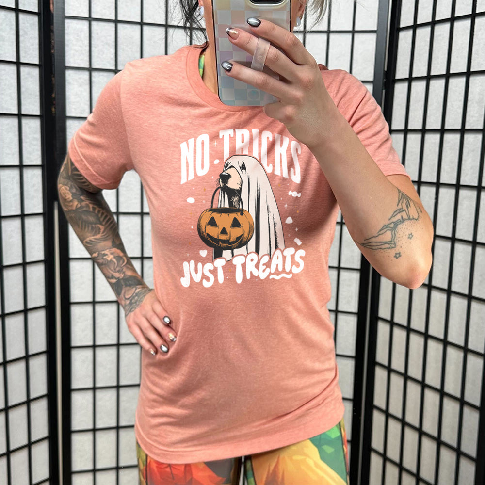 Model wearing sunset colored shirt with dog wearing a sheet and a candy bucket in its mouth graphic on it that says "No Tricks Just Treats"