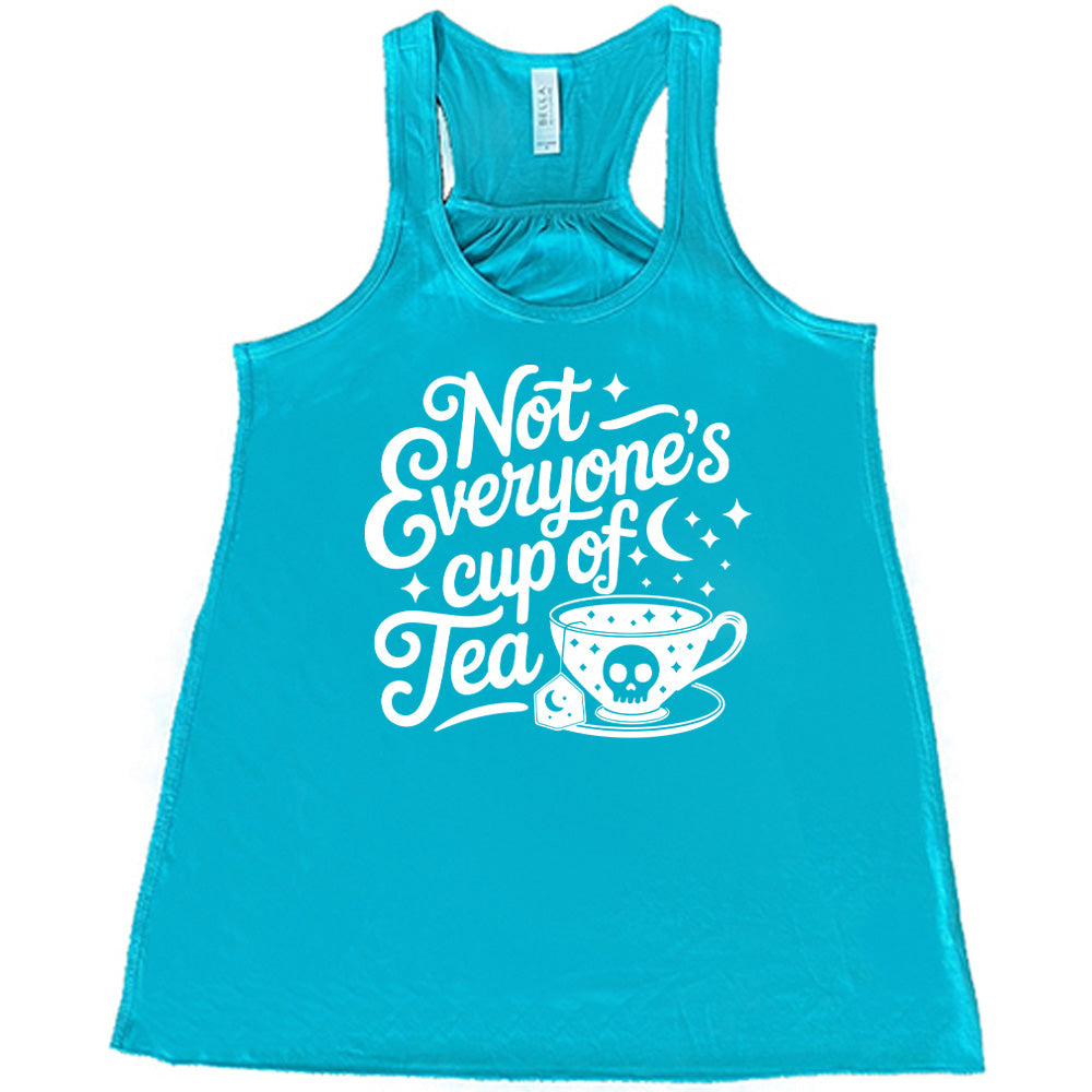 teal flowy tank with the words "not everyone's cup of a tea" in a cursive font, with the graphics of a moon and little stars, and a tea cup with a skull on it with stars and the tea bag has a moon on it