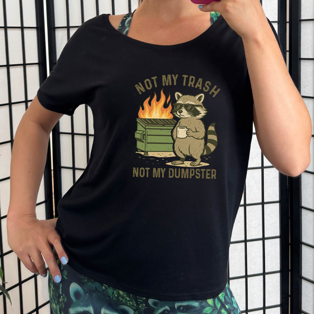black slouchy tee with the words "not my trash not my dumpster" and the graphic of a racoon with sunglasses drinking coffee in front of a dumpster that's on fire