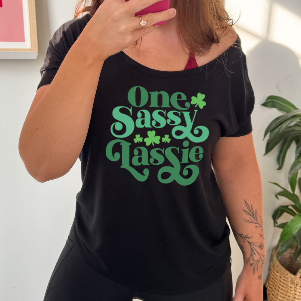 black slouchy tee with the words "one sassy lassy" on it, with a few shamrock graphics