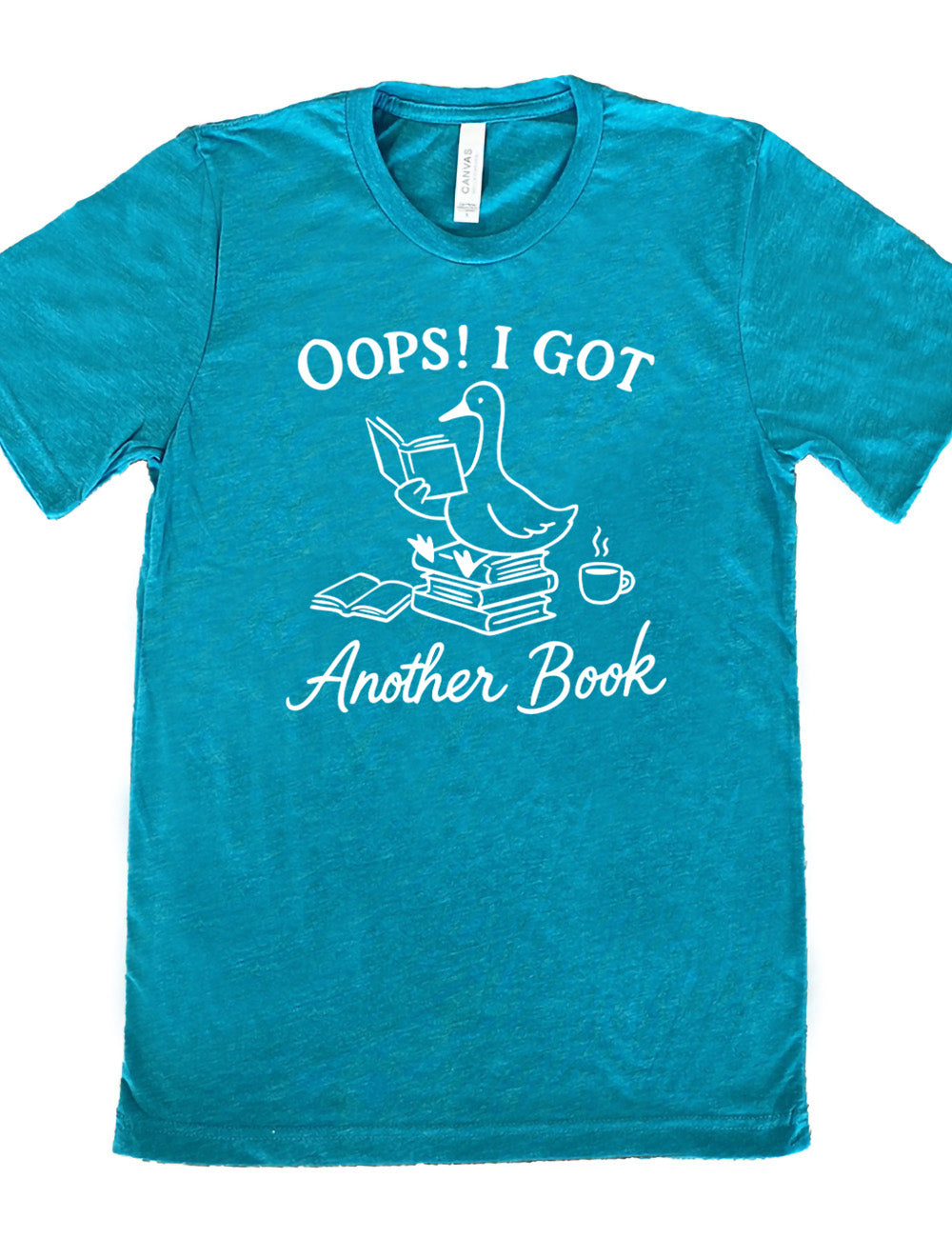 teal unisex tee with the graphic of a goose, sitting on a stack of books, reading a book, with another book open beside the stack, and a steaming cup of coffee on the other side, with the words around the graphic saying "Oops! I got another book" 