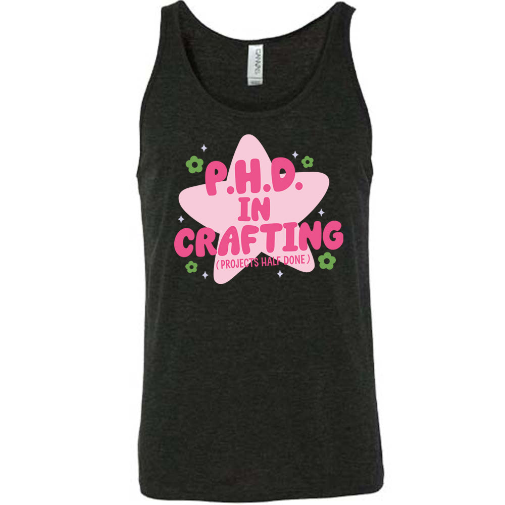black unisex tank with cartoon graphic of a large star behind the words "P.H.D.  in Crafting" in large font with the words (Projects Half Done) in small font underneath, with very small flowers and stars around
