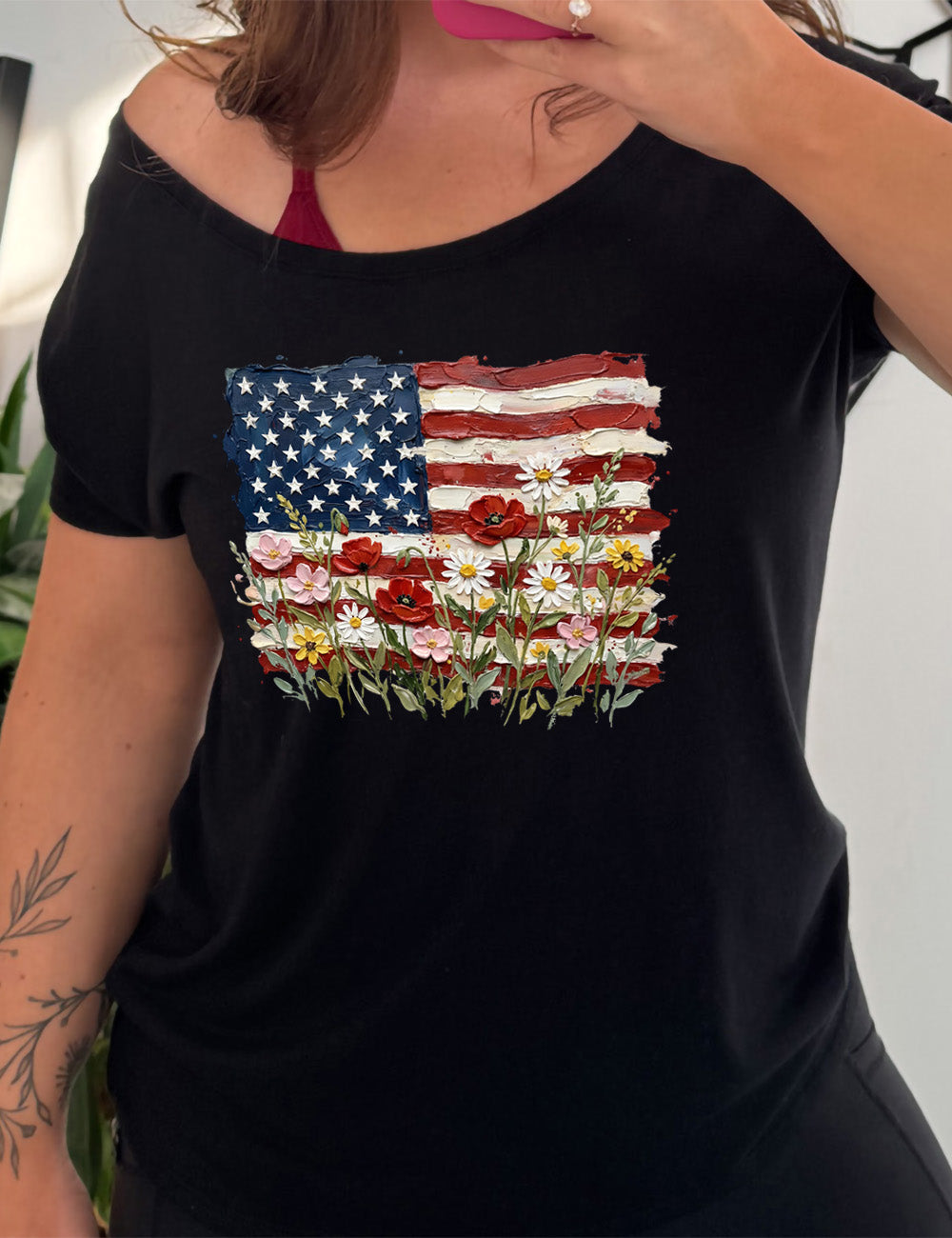 black slouchy tee with the graphic of an American flag with flowers in front of it, with the style of the graphic looking made of oil paint 