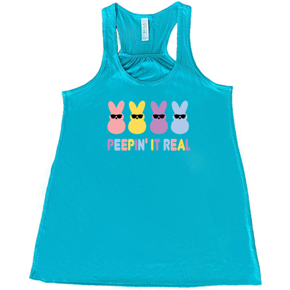 Teal colored flowy tank with an Easter-colored bunnies graphic on it that says "Peepin it Real" 