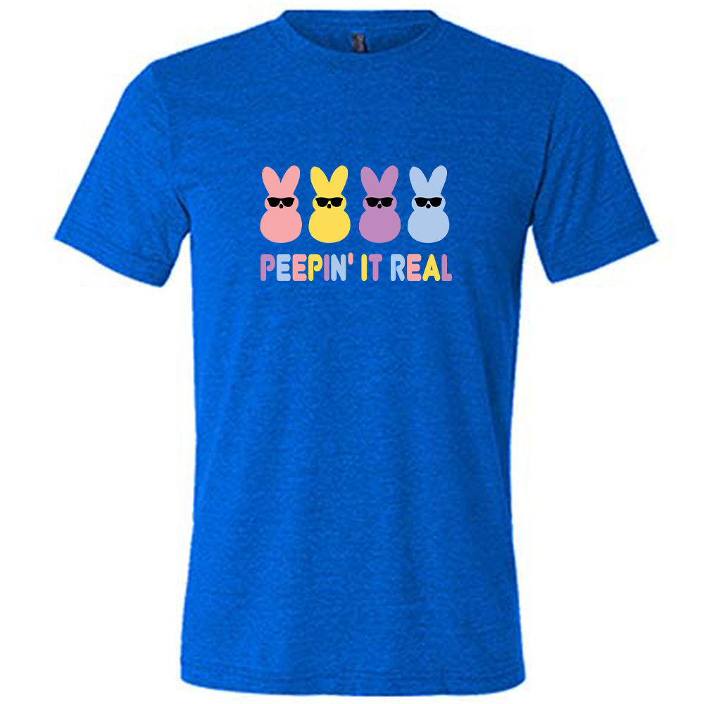 Blue colored shirt with an Easter-colored bunnies graphic on it that says "Peepin it Real" 