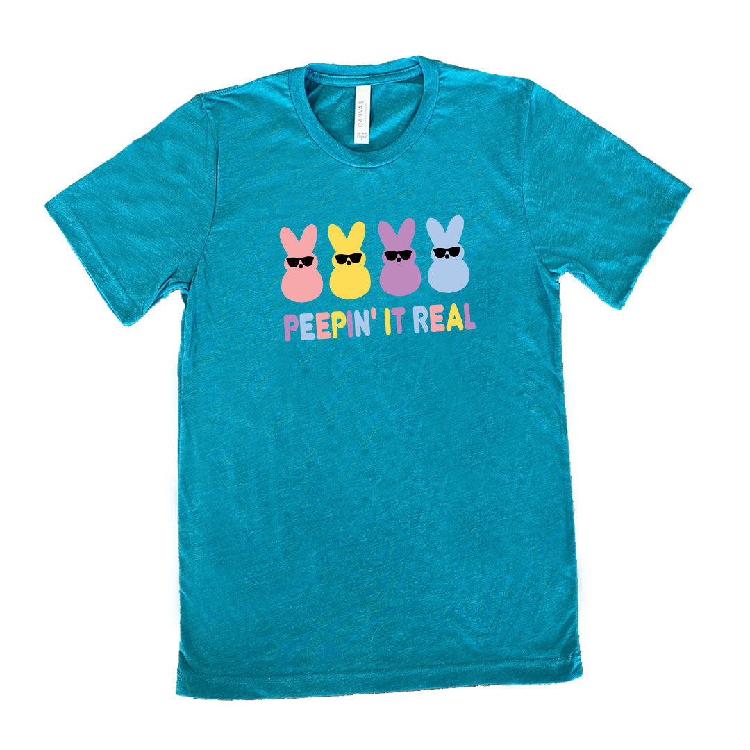 Teal colored shirt with an Easter-colored bunnies graphic on it that says "Peepin it Real" 