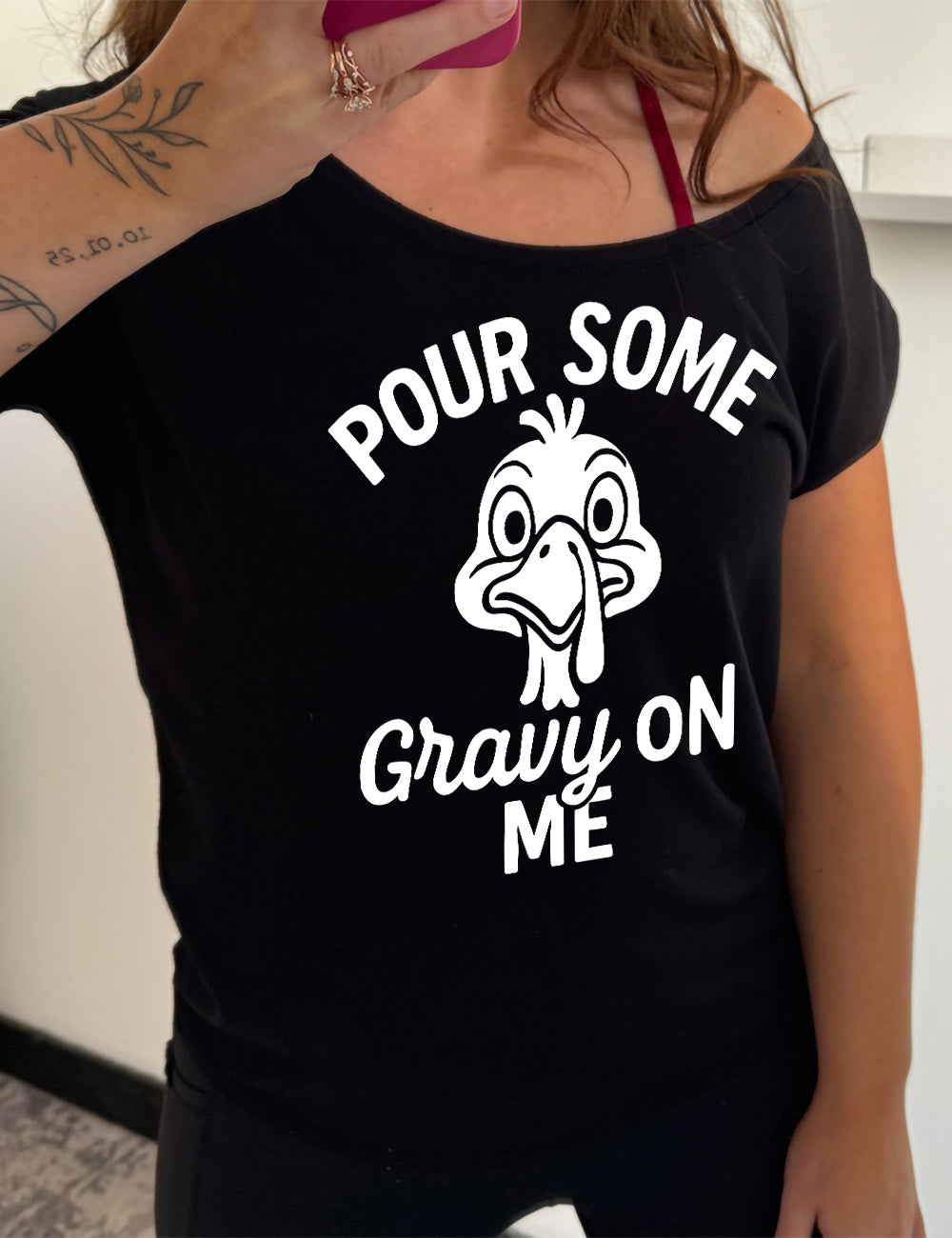black slouchy tee with the words "pour some gravy on me" on it, with "gravy" in cursive", and the words "pour some" slightly arching over the graphic of a turkey's head, eyes wide