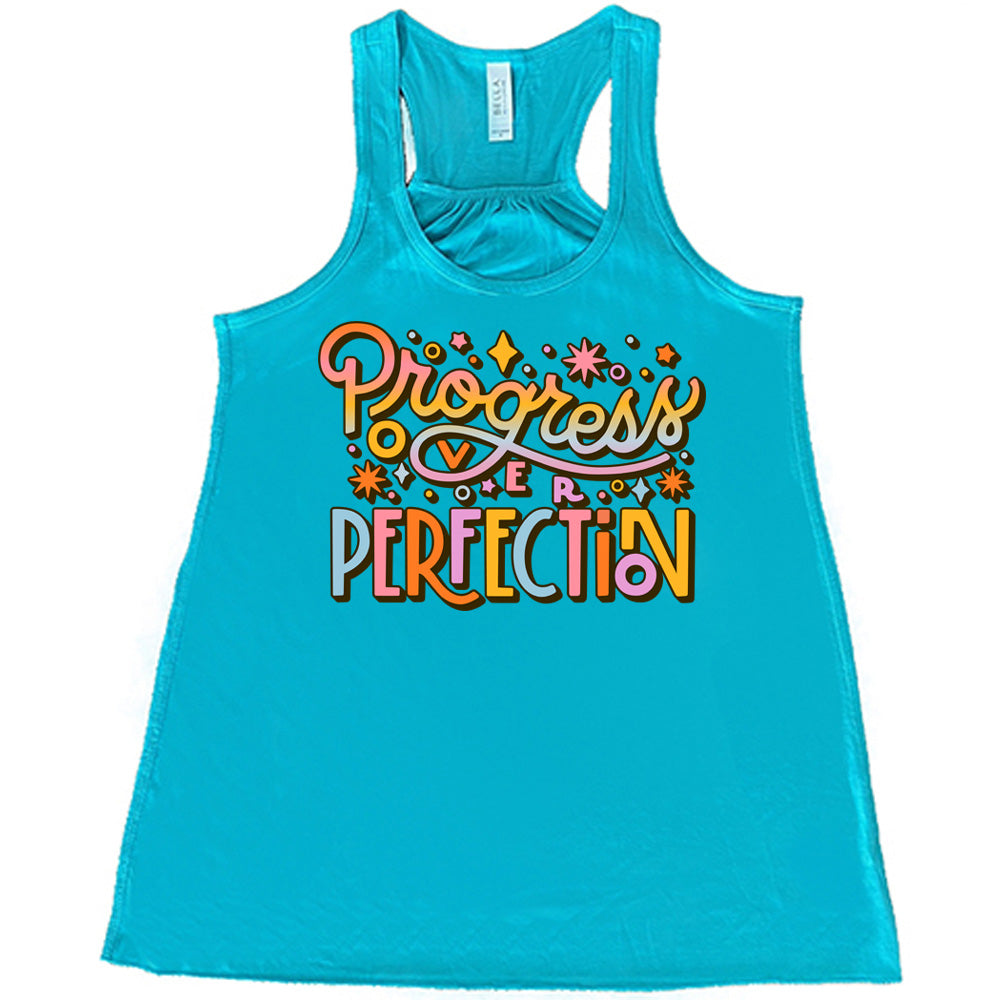 Teal flowy tank with Progress Over Perfection written in colorful lettering, with various stars